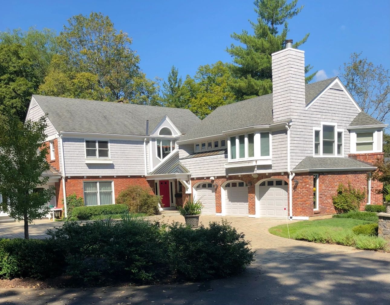 A gray-sided home with white trim and brick from Andrews Painting Company’s exterior project gallery.